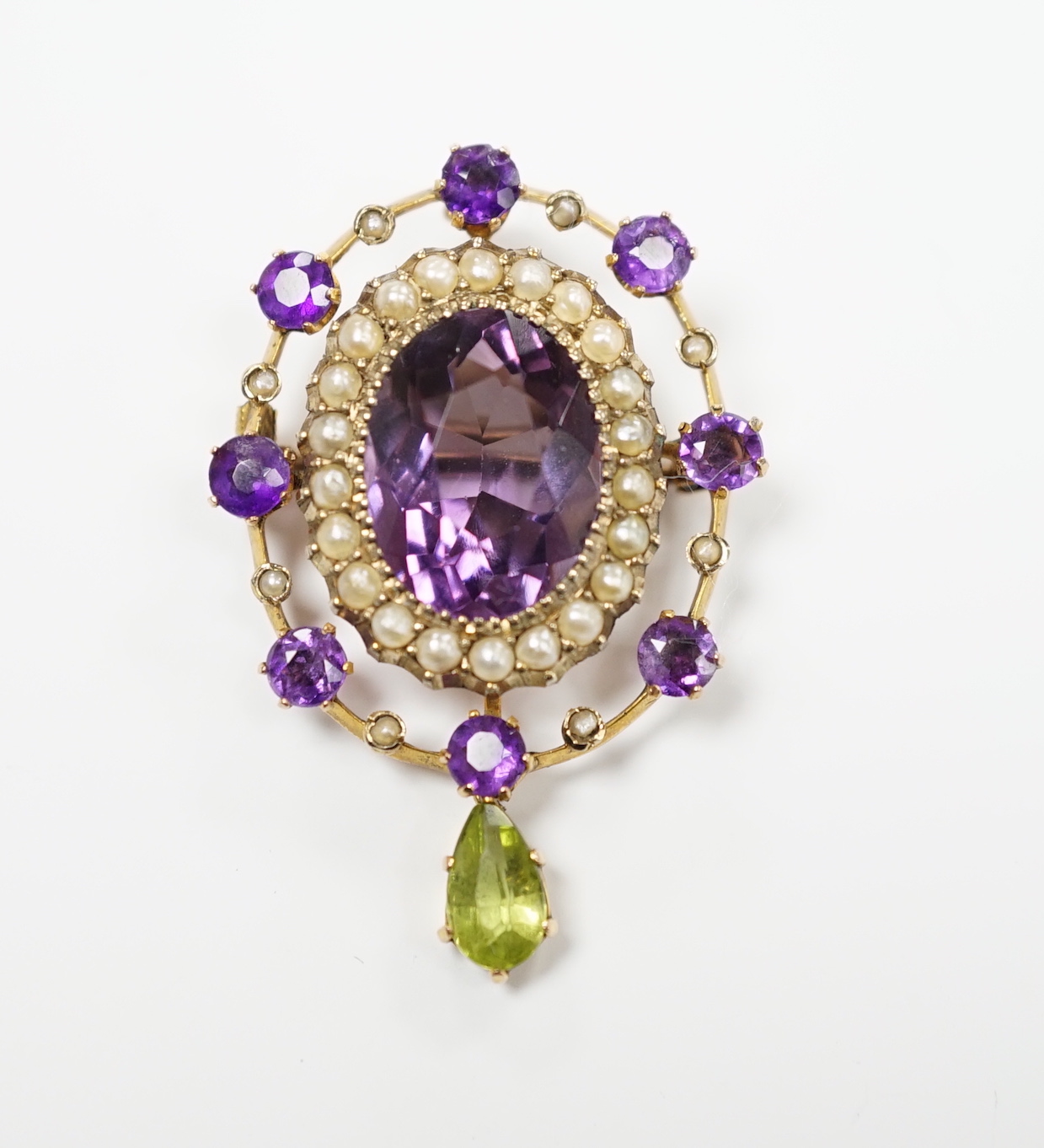 An early 20th century yellow metal, amethyst, peridot and seed pearl cluster set drop pendant brooch, 35mm, gross weight 4.9 grams.